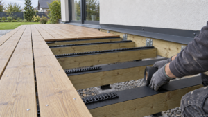 Daļēji izbūvēta koka terase pie mājas ar TERRACE Core EPDM lentu un TERRACE Vent profiliem zem terases dēļiem